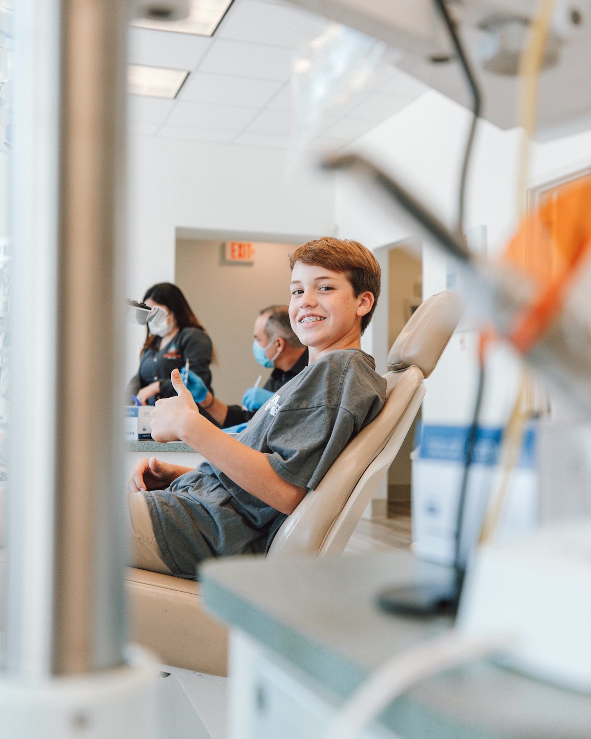 Un bambino sorridente fa il pollice in su su una sedia da dentista.