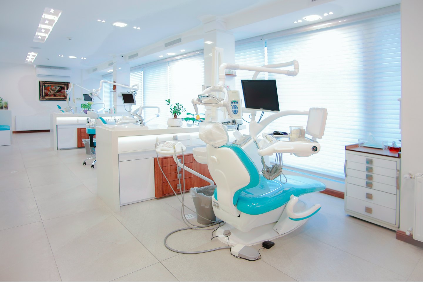 Interno di una moderna clinica dentale con sedie turchesi e bianche.